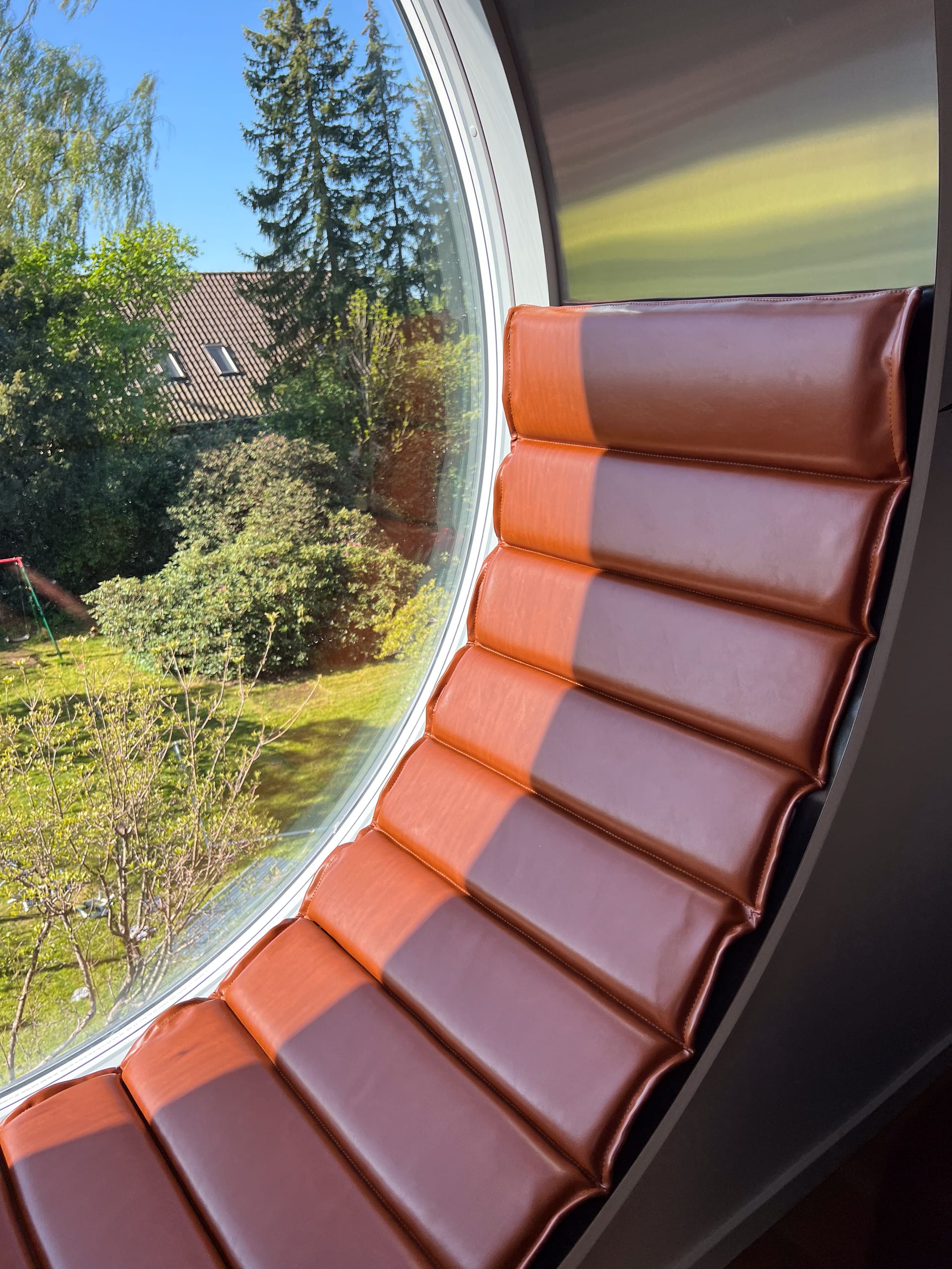 Hynde på mål i vinduesparti med runde vinduer og udsigt over haven